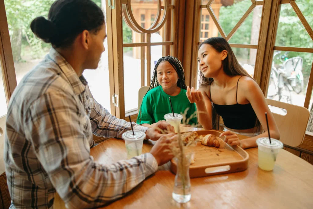 Pessoas compartilham uma refeição e conversam à mesa em casa.